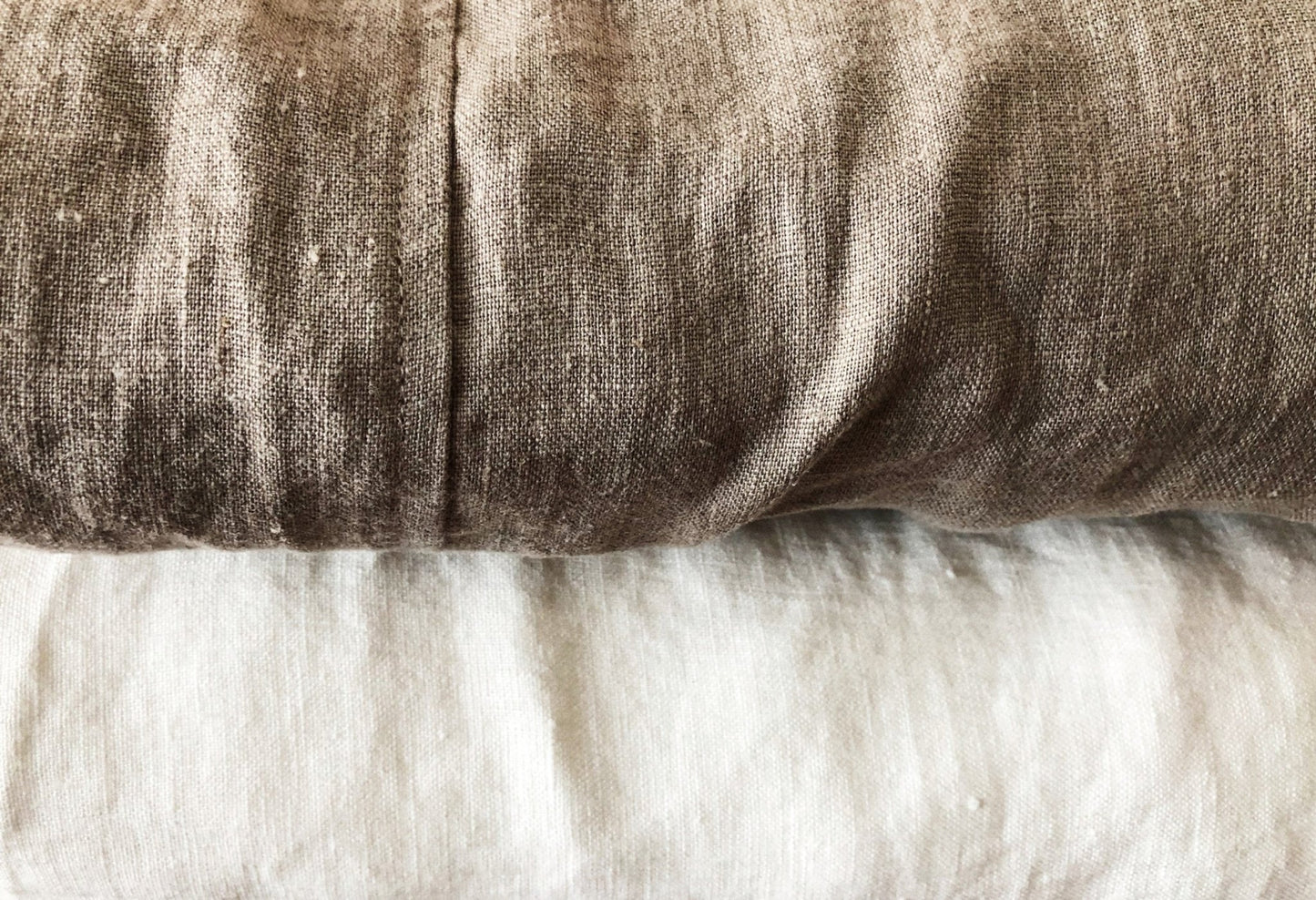 Close up of plump folded queen sized textured Oeko-Tex Certified Organic Linen Fitted Sheets in natural flax and off-white from Rural Route Seven brand
