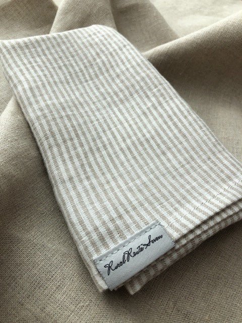 folded White with Natural Flax Stripes Linen Tea Towel with Rural Route Seven brand label, on open natural flax tea towel