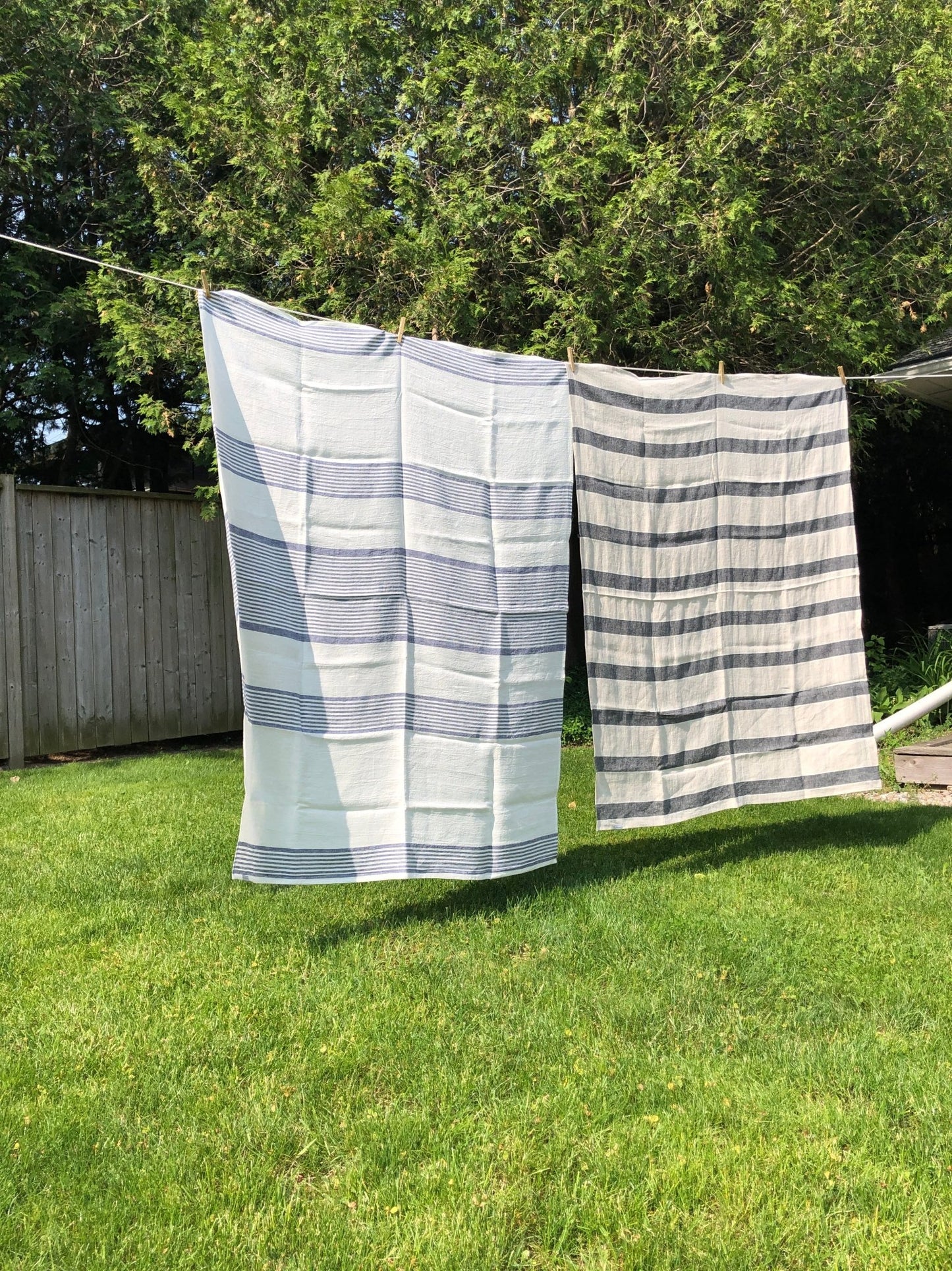 linen huckaback beach towels on clothesline with green grass and trees background