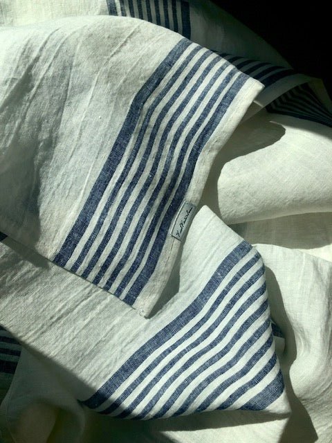 white and blue striped linen huckaback towel in gentle folds in sunlight
