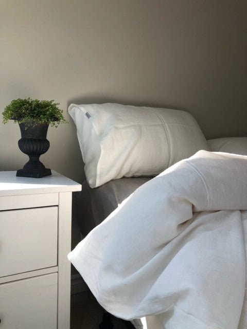 Turned down bed with white linen duvet and natural linen sheet