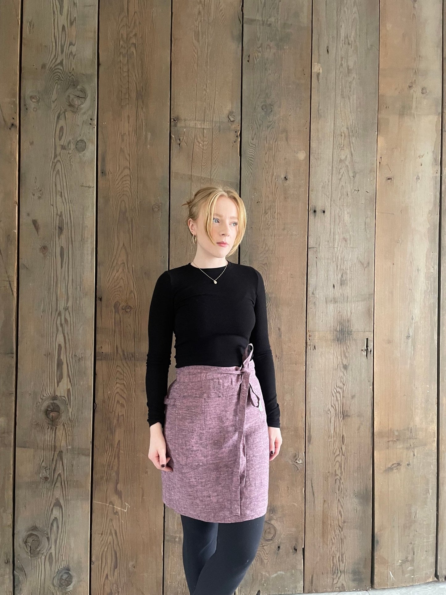 Young woman wearing linen half apron in pink black melange 