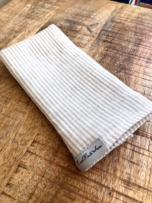 folded White with Natural Flax Stripes Stonewashed Linen Tea Towel with Rural Route Seven brand label, on antique pine table 