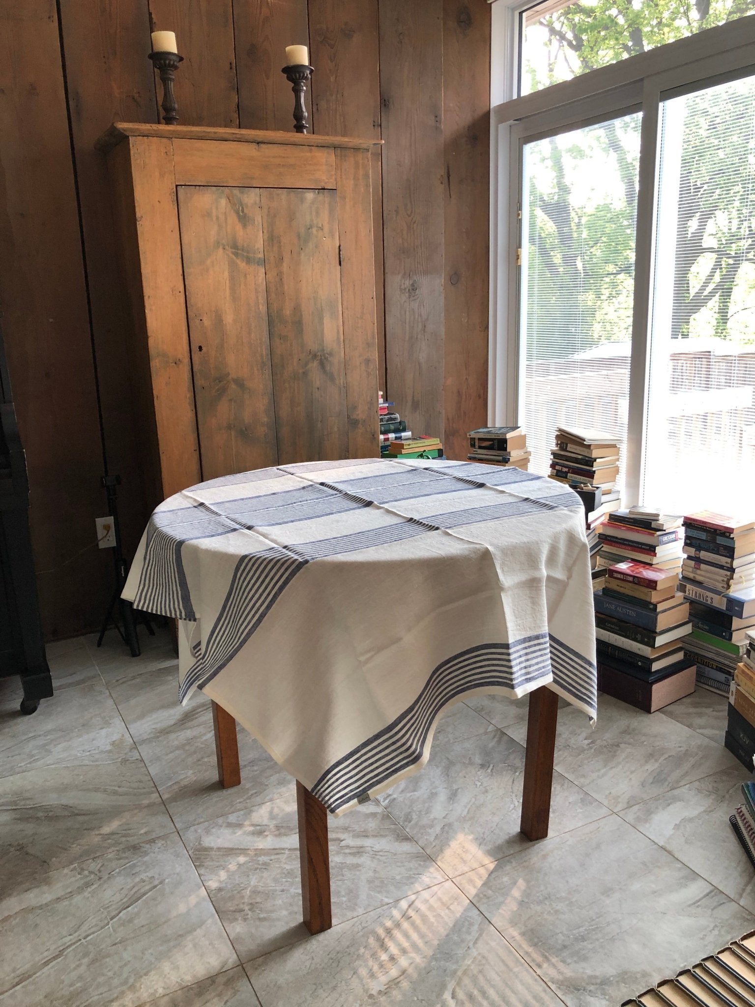 white with blue stripes huckaback linen beach towel used as tablecloth on round table in sunny room