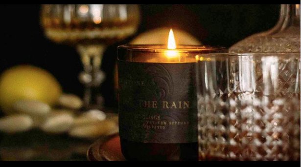 lit candle in moody scene with scotch glasses