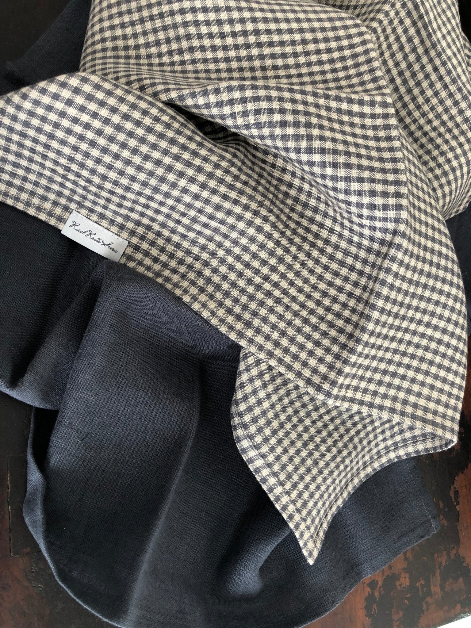 Small charcoal grey and natural flax checked linen tea towel and charcoal grey  linen tea towel on distressed black cupboard